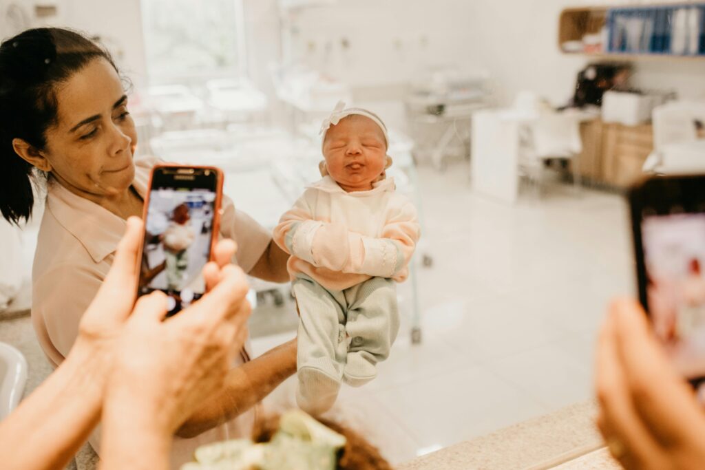 Newborn baby held by a nurse as family captures the moment in a hospital.