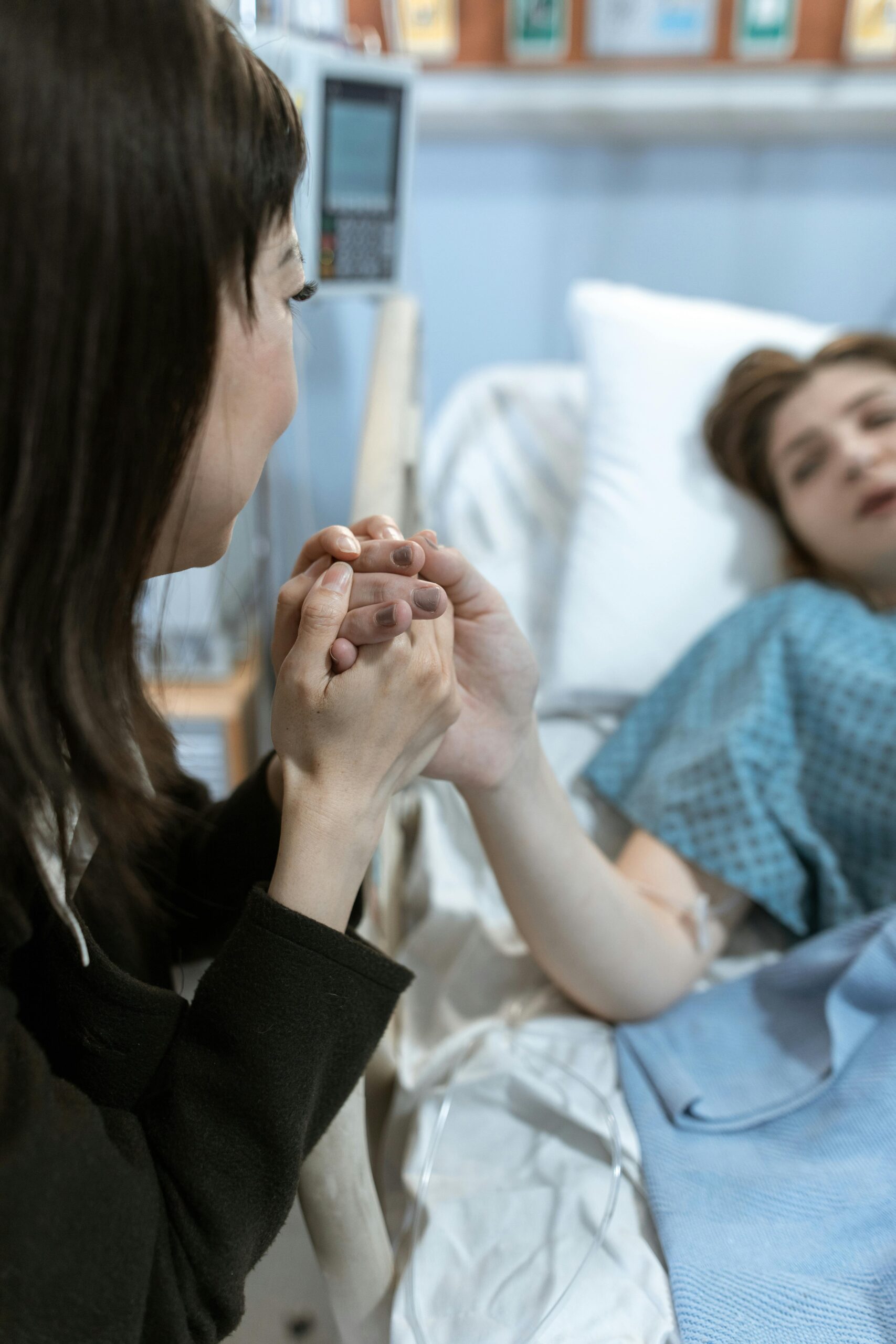Woman holding patient's hand in hospital, providing comfort and care.